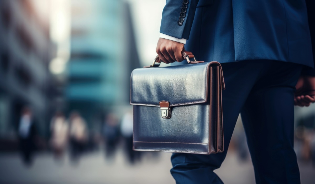 Man walks towards an office building with a suitcase.